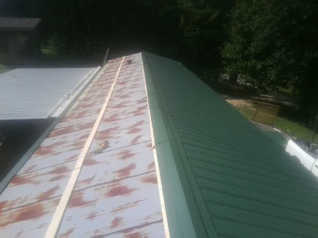 Old rusted panels beside newly installed green metal roofing — Wind Damage Roof Repair by Roofing Brothers in New Holland