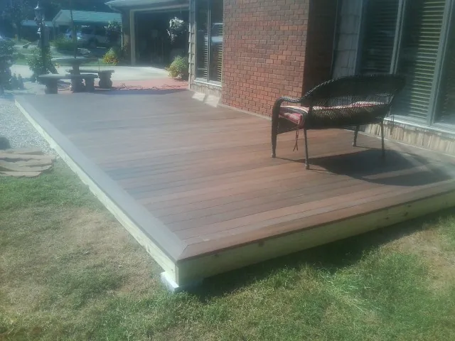 New wood deck and wicker chair beside a brick house in New Holland